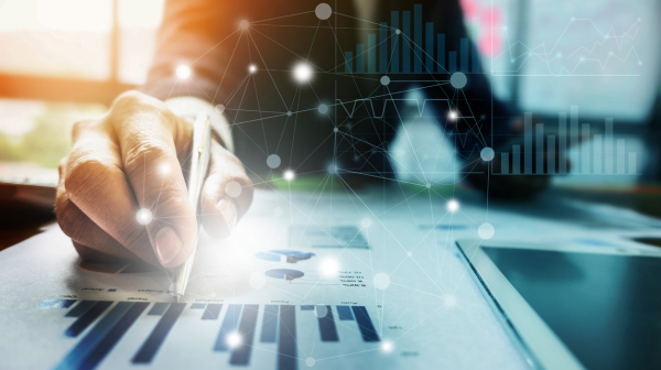 Close up Businessman hand holding pen and pointing at financial paperwork with financial network diagram.